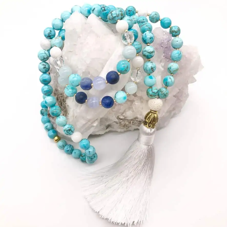 turquoise mala necklace with white tassel on top of selenite