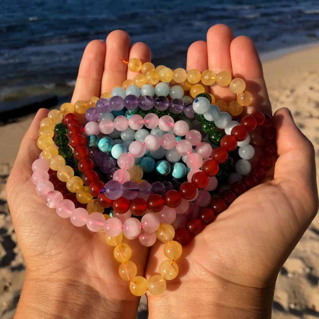 women holding Custom Mala Jewelry gemstones at beach