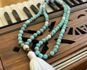 turquoise mala necklace with white tassel on harmonium